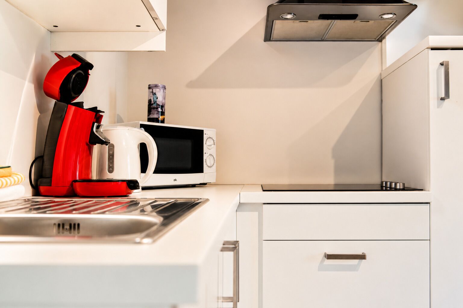 Une cuisine moderne équipée d’un four à micro-ondes, d’une bouilloire et d’une machine à café.