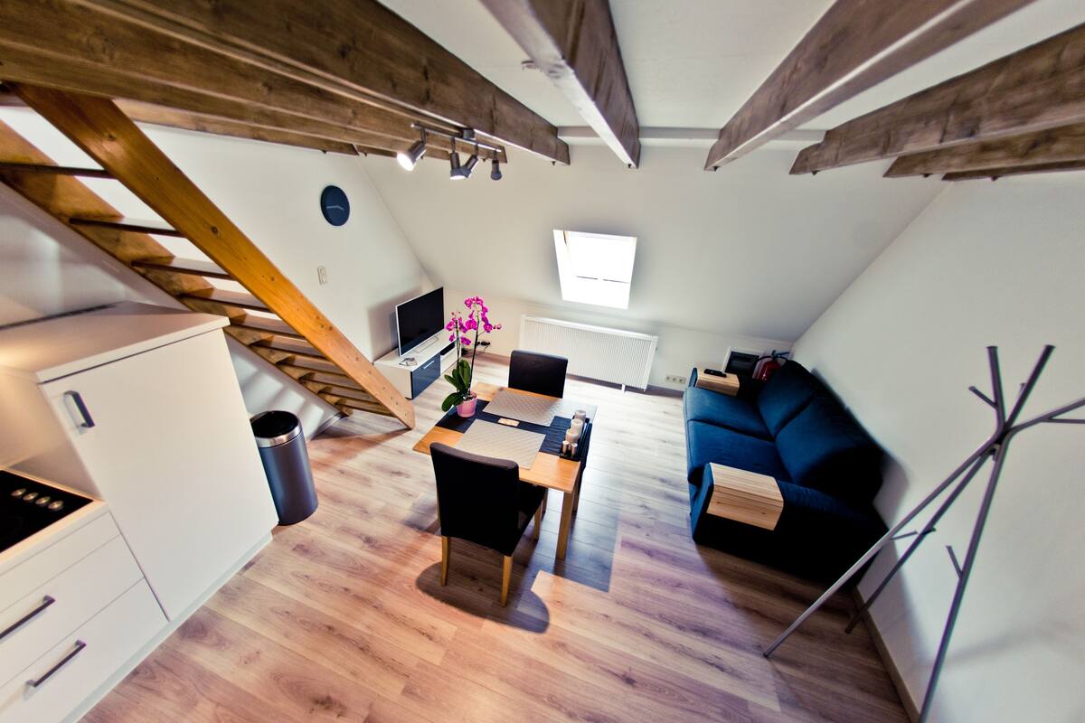 A modern loft apartment with a dining area, kitchen, and living space.