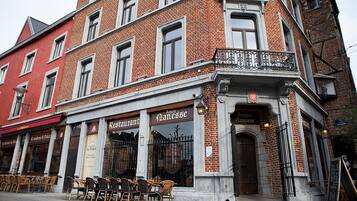 Een hoekpand met op de begane grond een restaurant genaamd "Amon Panisse". Er staan zitplaatsen buiten voor het restaurant.