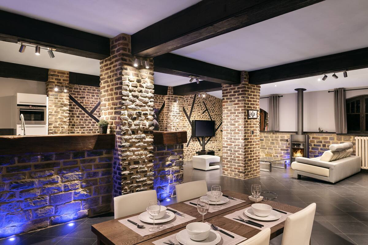 A modern kitchen with a stone wall, a fireplace, and a dining area with a table set for two.