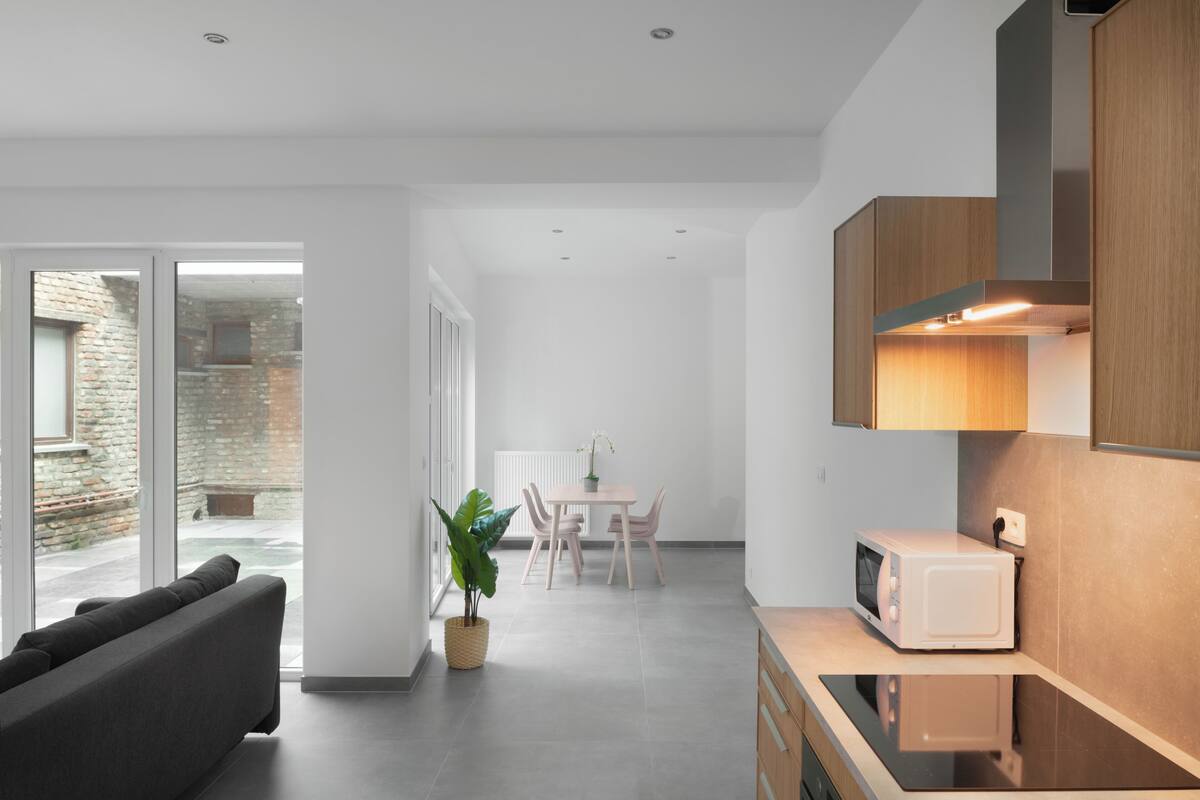 A modern kitchen with a microwave, wooden cabinets, and a dining area with a table and chairs.