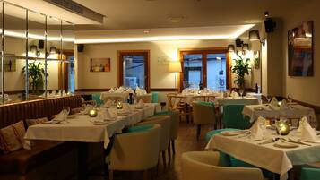 Un restaurante con varias mesas dispuestas para comer, que presenta un interior cálido con detalles de madera y sillas color turquesa.