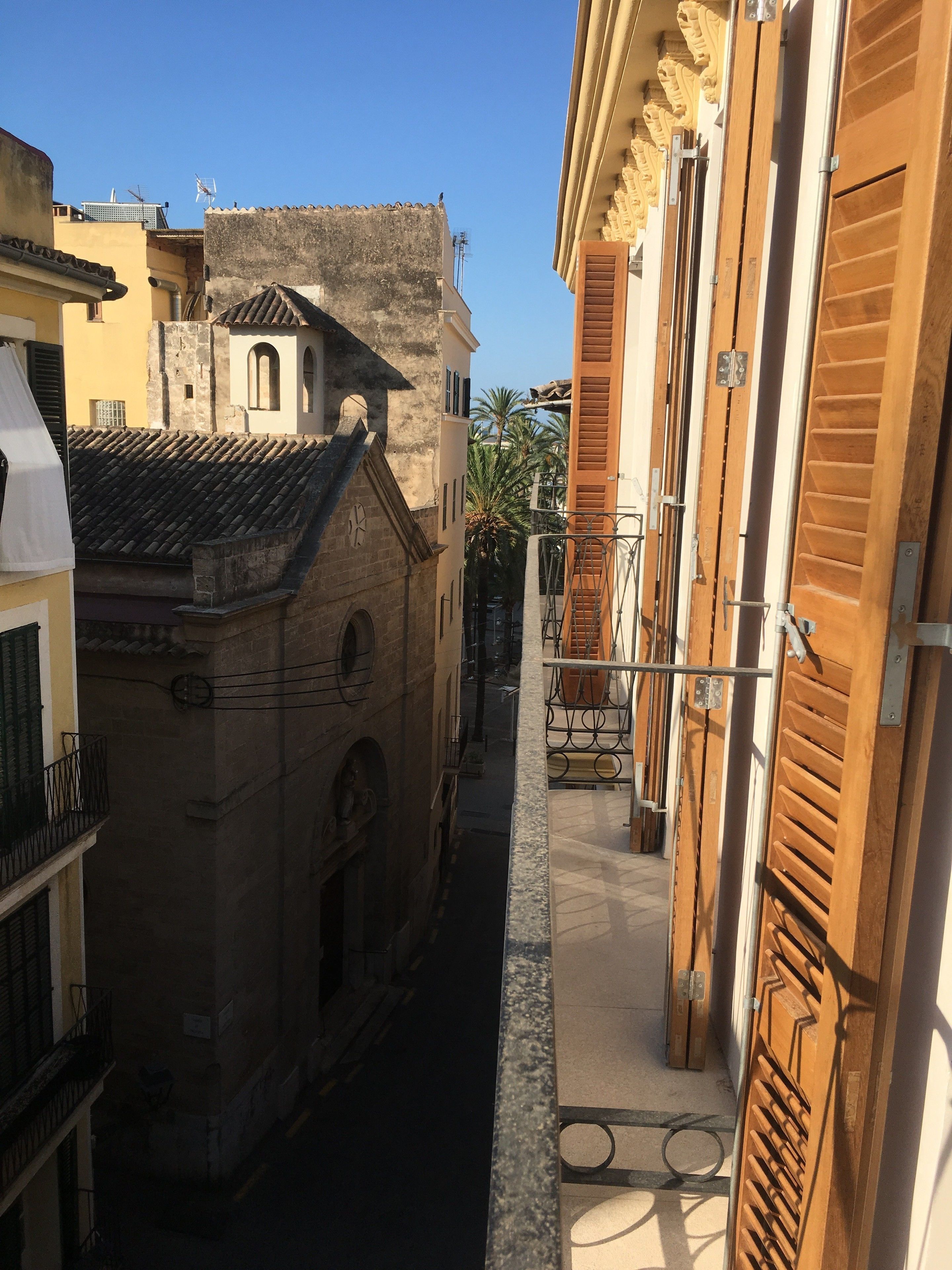 Une rue étroite bordée de bâtiments des deux côtés, caractérisée par une architecture traditionnelle et un ciel d’un bleu éclatant.