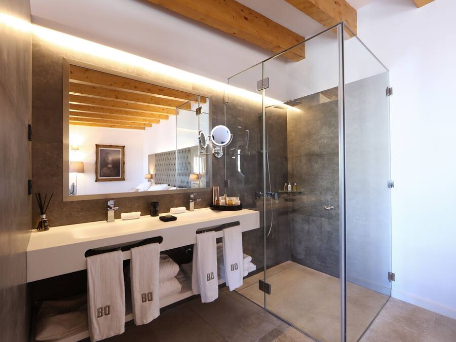 Un baño moderno con ducha de vidrio, un espejo grande y techo de madera.