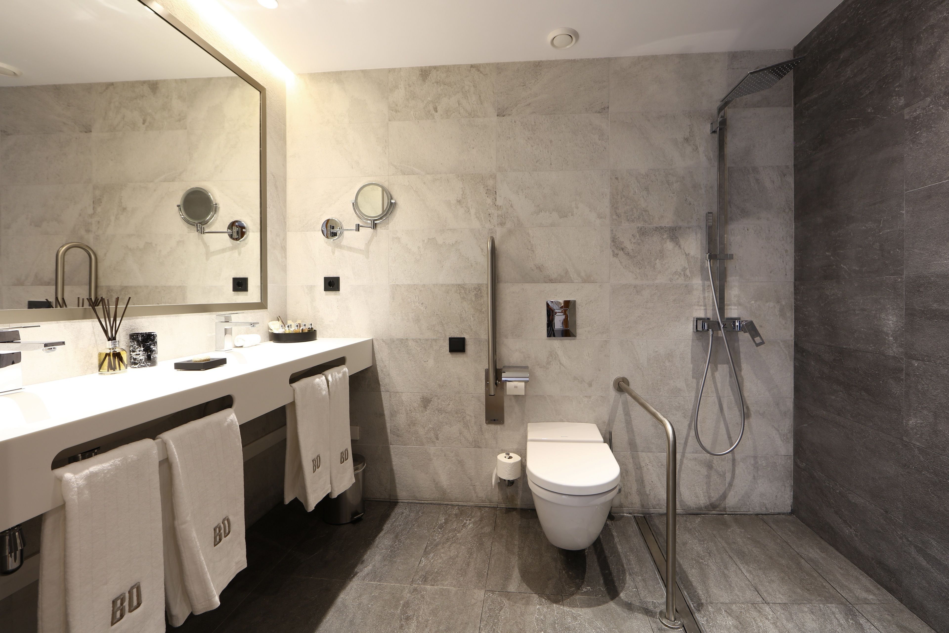 Un baño moderno con un espejo grande, lavamanos dobles, inodoro y zona de ducha.