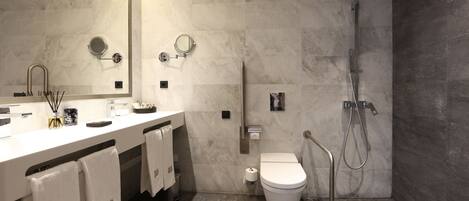 A modern bathroom with a large mirror, dual sinks, a toilet, and a shower area.