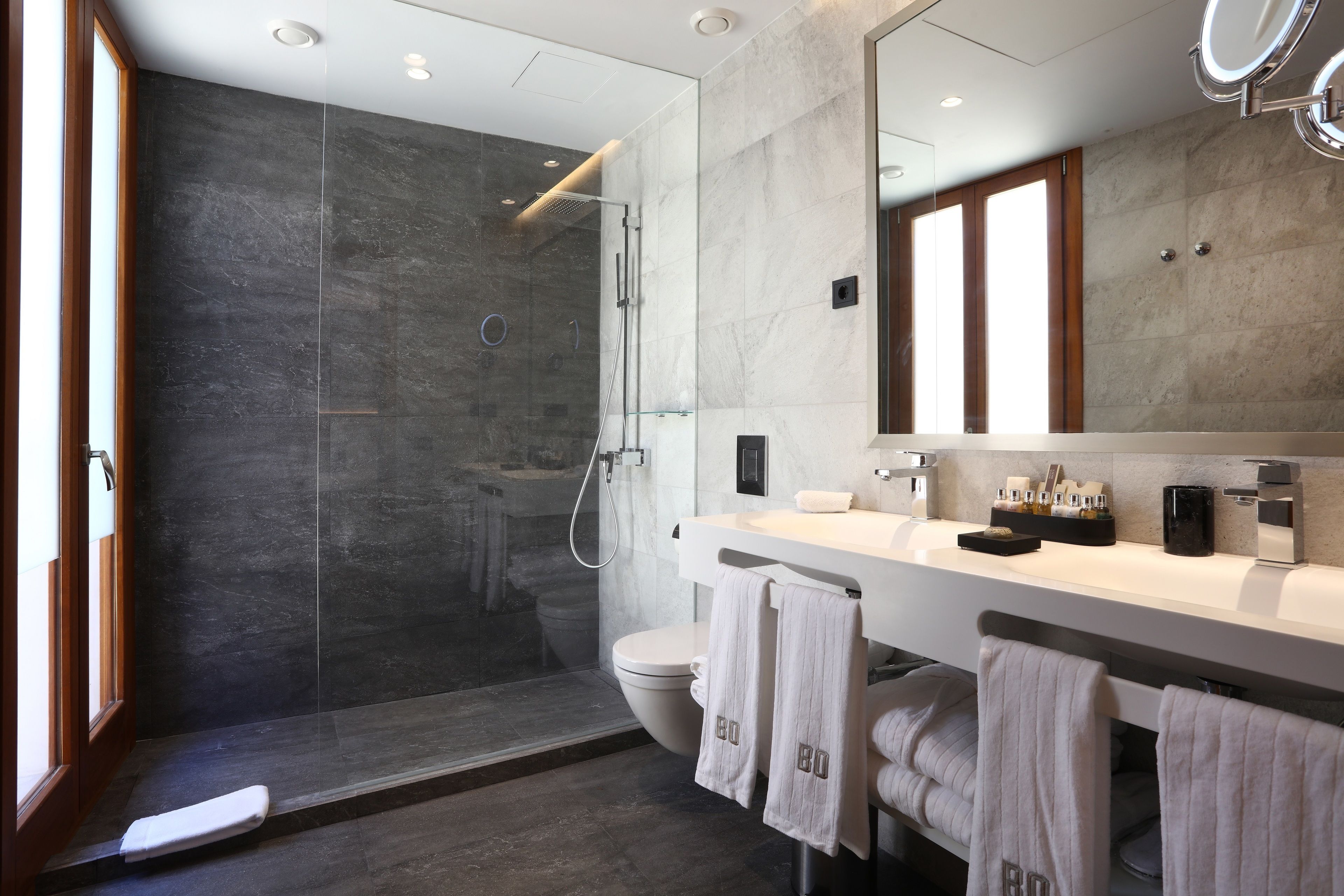 A modern bathroom with a glass-enclosed shower, a white sink, and a large mirror.