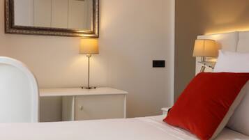 A hotel room with a bed, bedside tables, lamps, and a mirror.