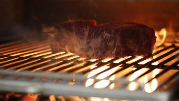 Ein Steak wird auf einem Grill mit sichtbaren Flammen zubereitet.