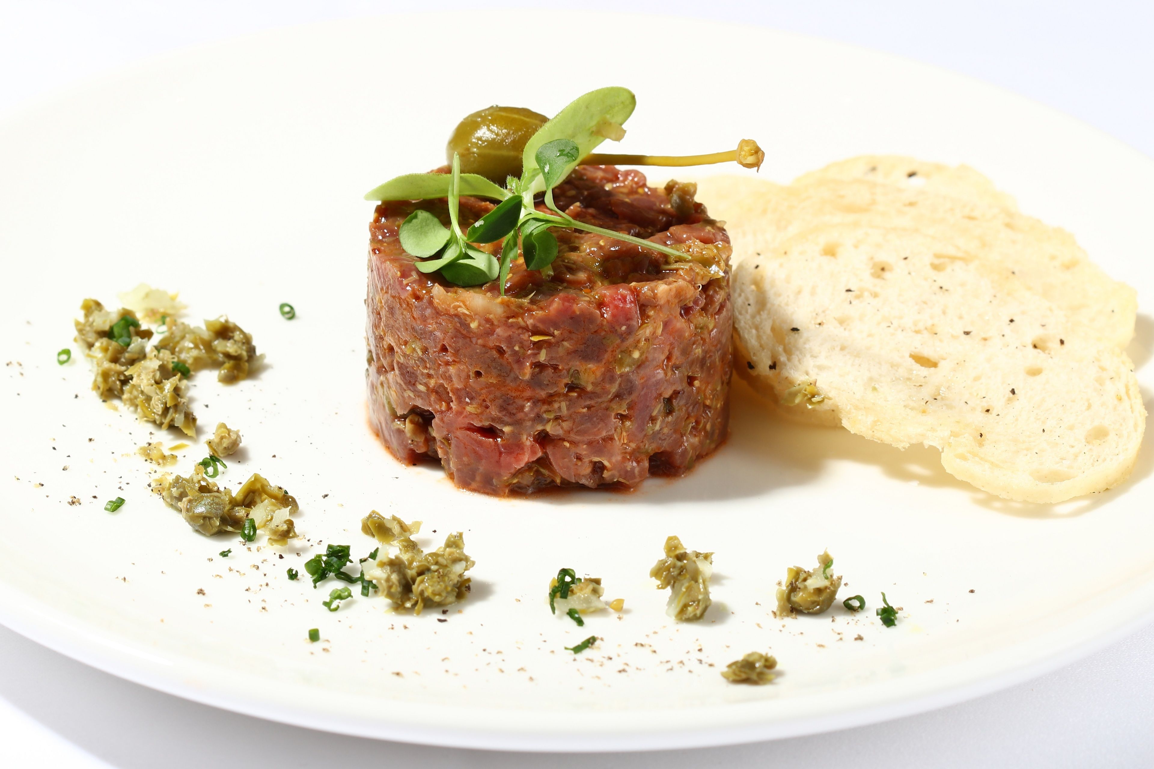 Un plato con carne, guarnición verde y pan.