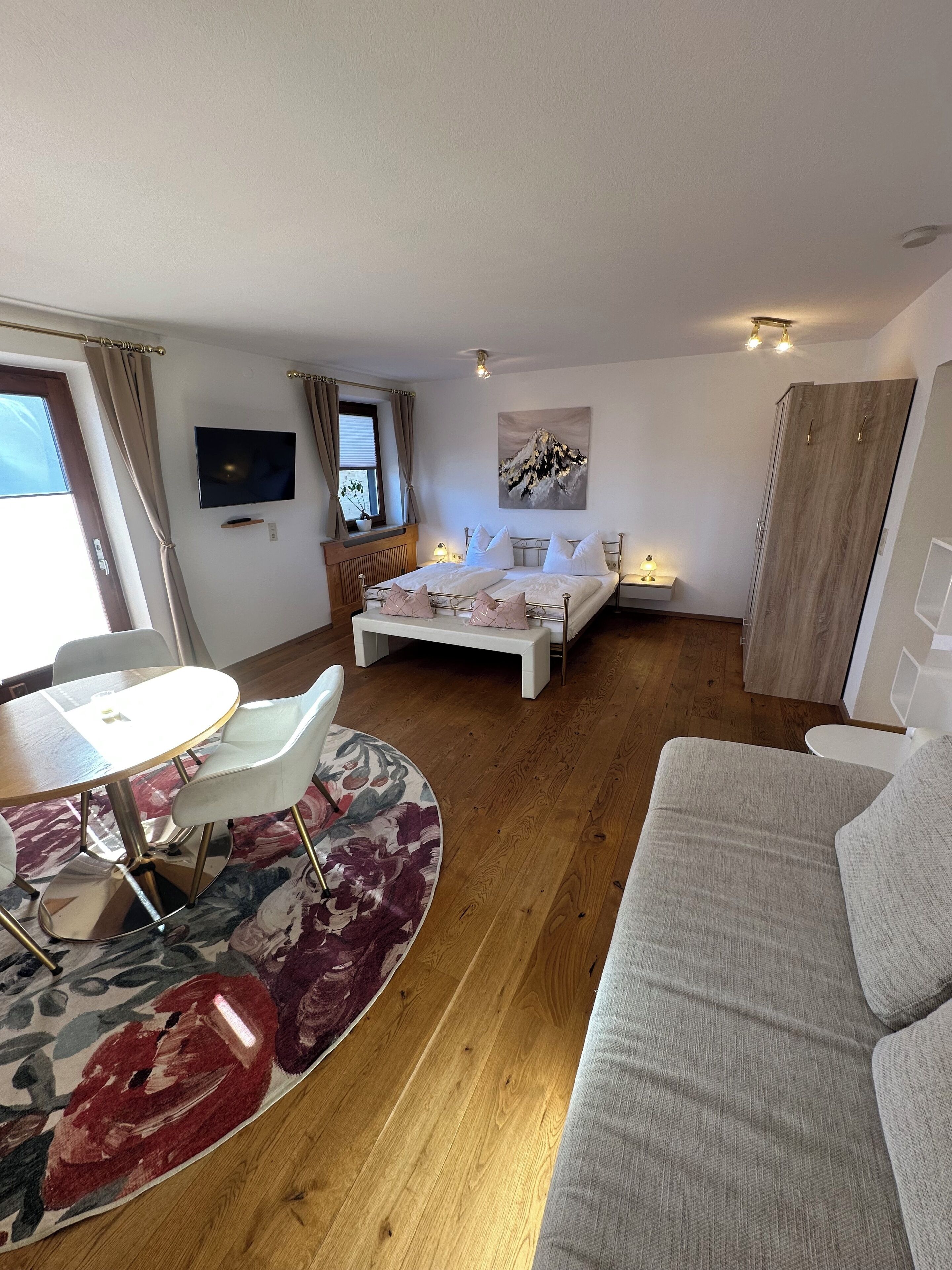 Una habitación de hotel moderna con cama, televisor, mesa de comedor y sofá.