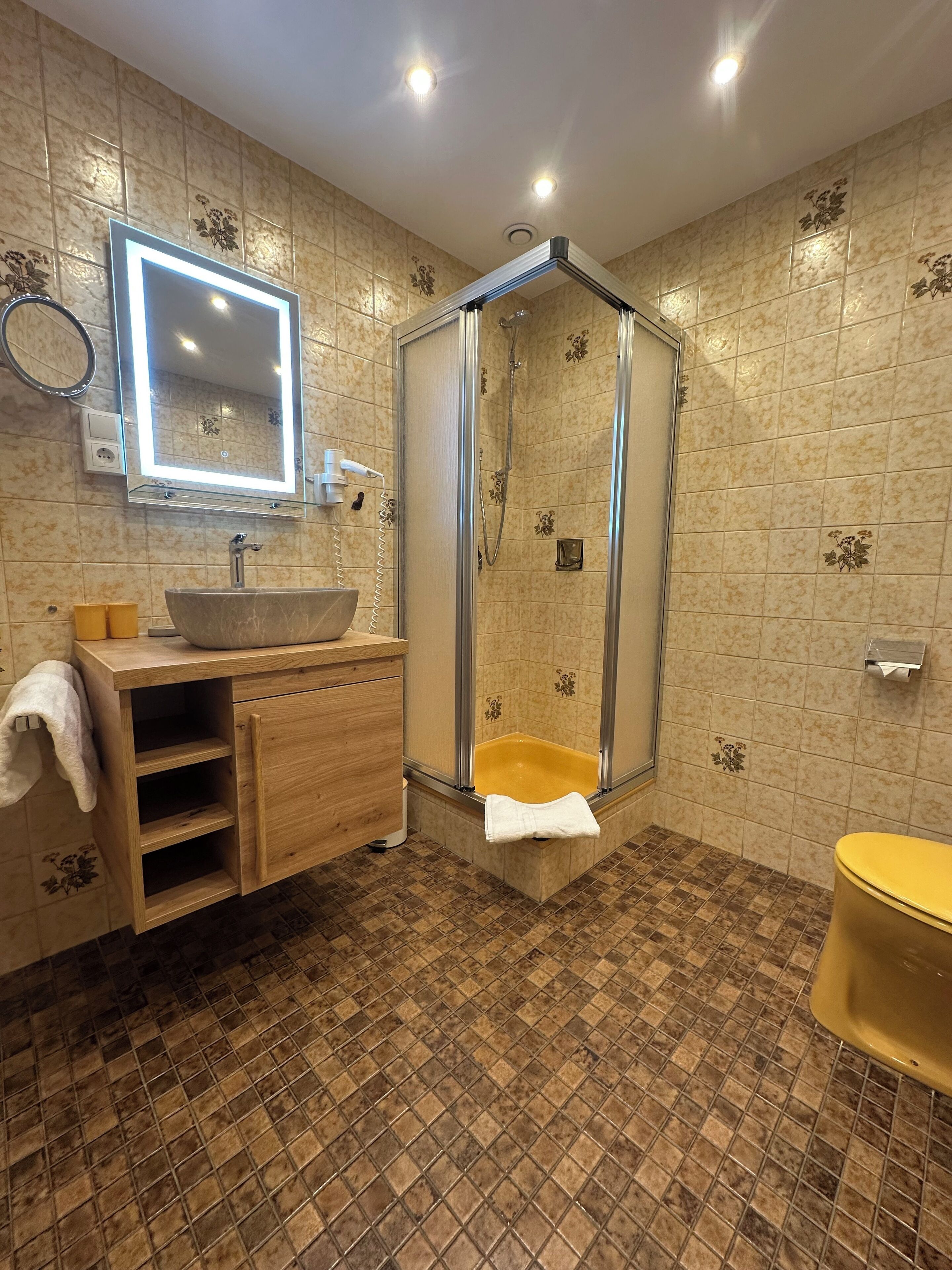 Un baño con tocador, lavabo, espejo, cabina de ducha y retrete.