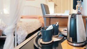 A hotel room with a bed, a desk with a computer, a coffee maker, and a tray with two mugs. - Villa Catelli B&B (Lucca)