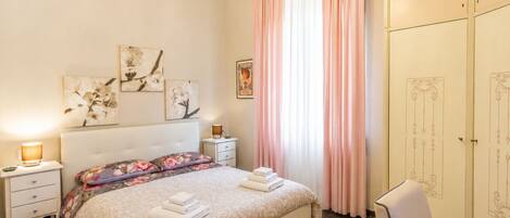 Une chambre à coucher comprenant un lit, des tables de chevet, une commode, une armoire et des œuvres d’art accrochées aux murs.