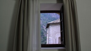 Una ventana con vistas a una montaña y un edificio con tejado de tejas.