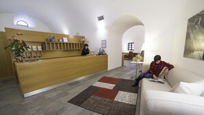 Un área de recepción con un escritorio de madera, una recepcionista y un espacio de espera con un sofá y una mesita de centro.