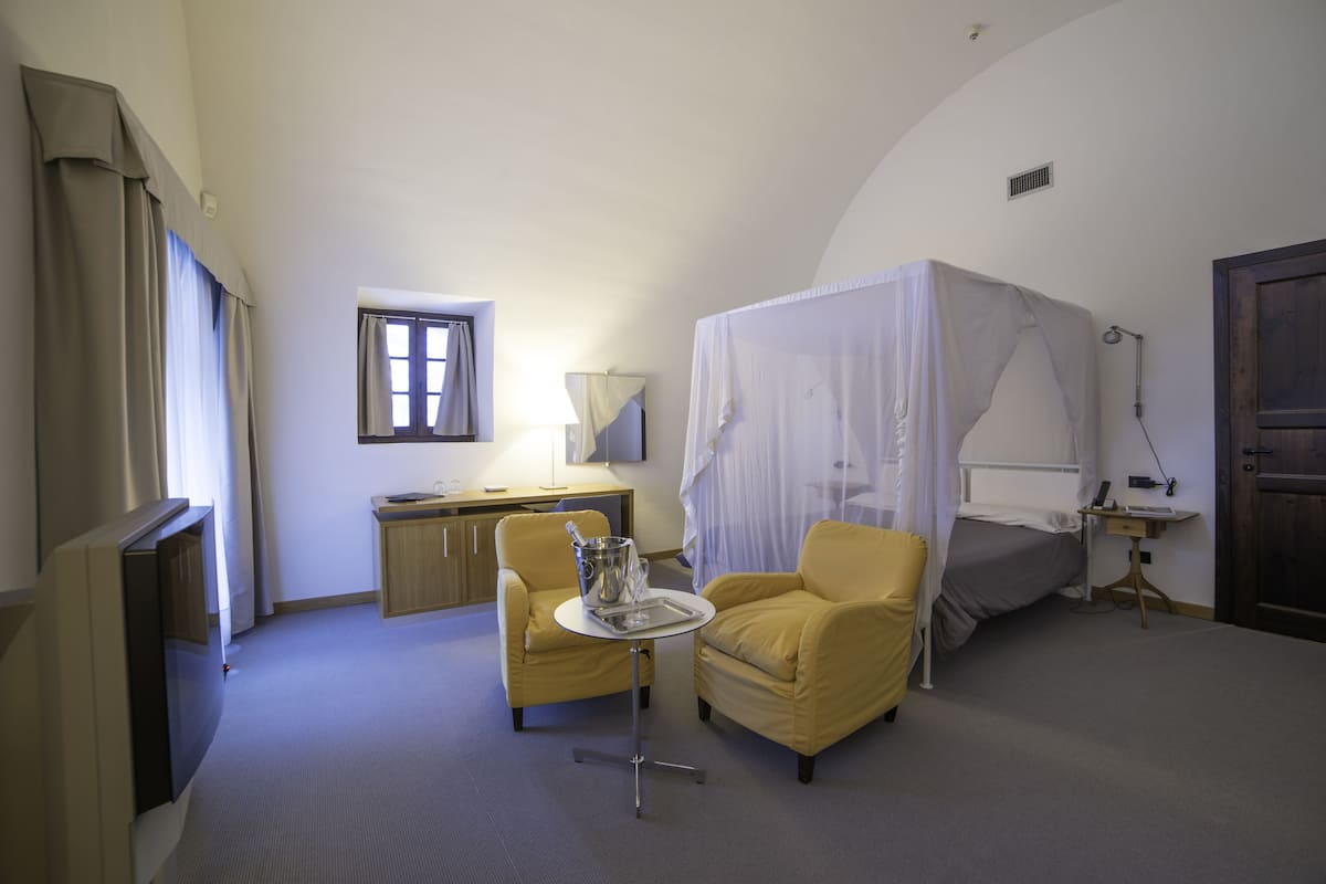 A hotel room with a bed, a desk, a chair, a television, and a window.