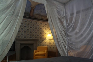 Ein Zimmer mit einem Bett, einem Sessel, einer Lampe und einem Kamin.