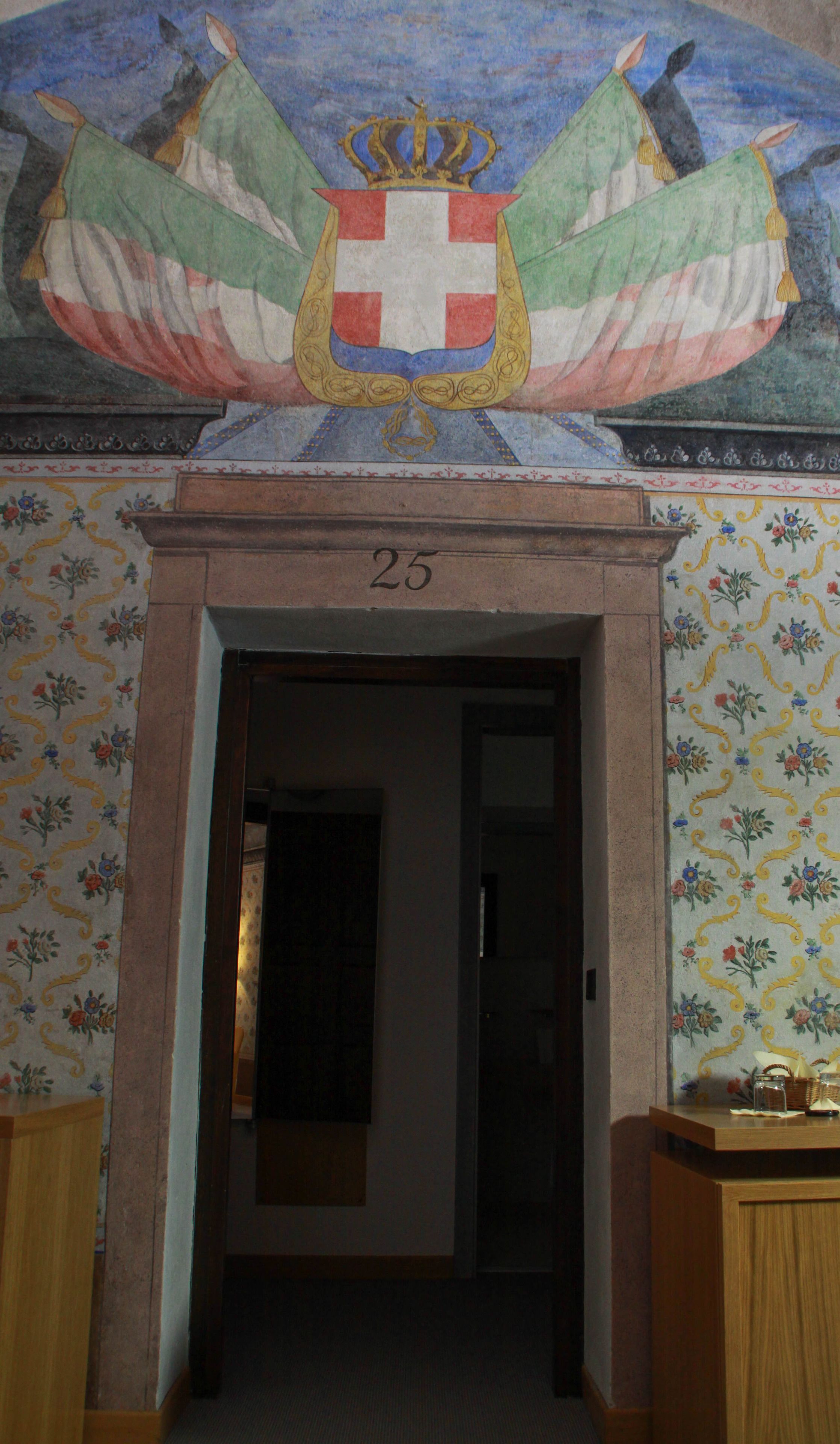 A doorway with a number '25' above it, leading to a room with floral wallpaper.