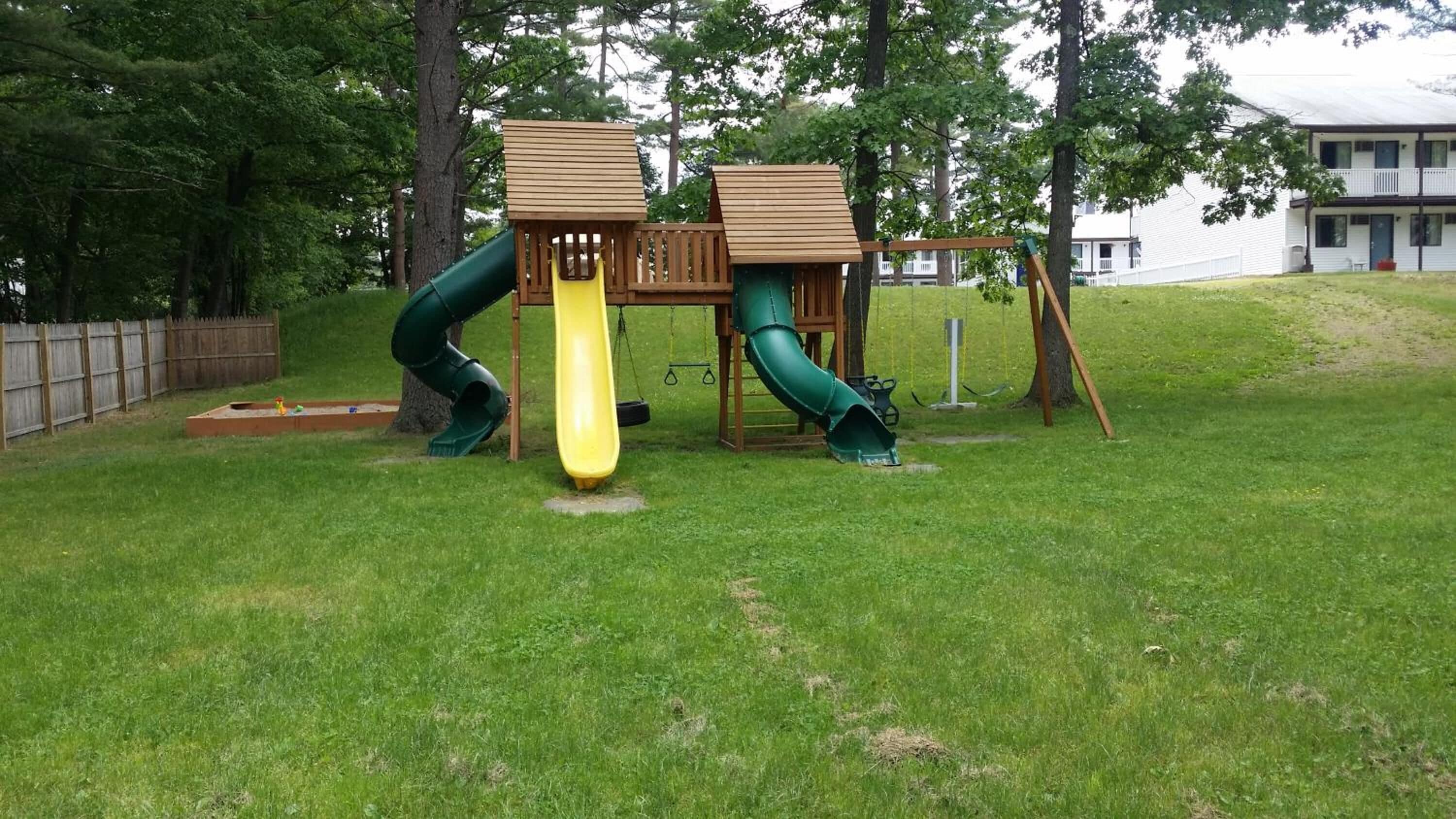 Un parque infantil con dos toboganes y una estructura de madera para escalar.