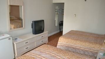 Habitación de hotel con dos camas, televisión, cómoda y espejo.