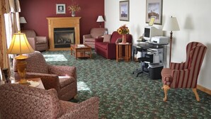 A living room with a fireplace, a desk with a computer, and a striped armchair. - Seabrook Inn (Seabrook)