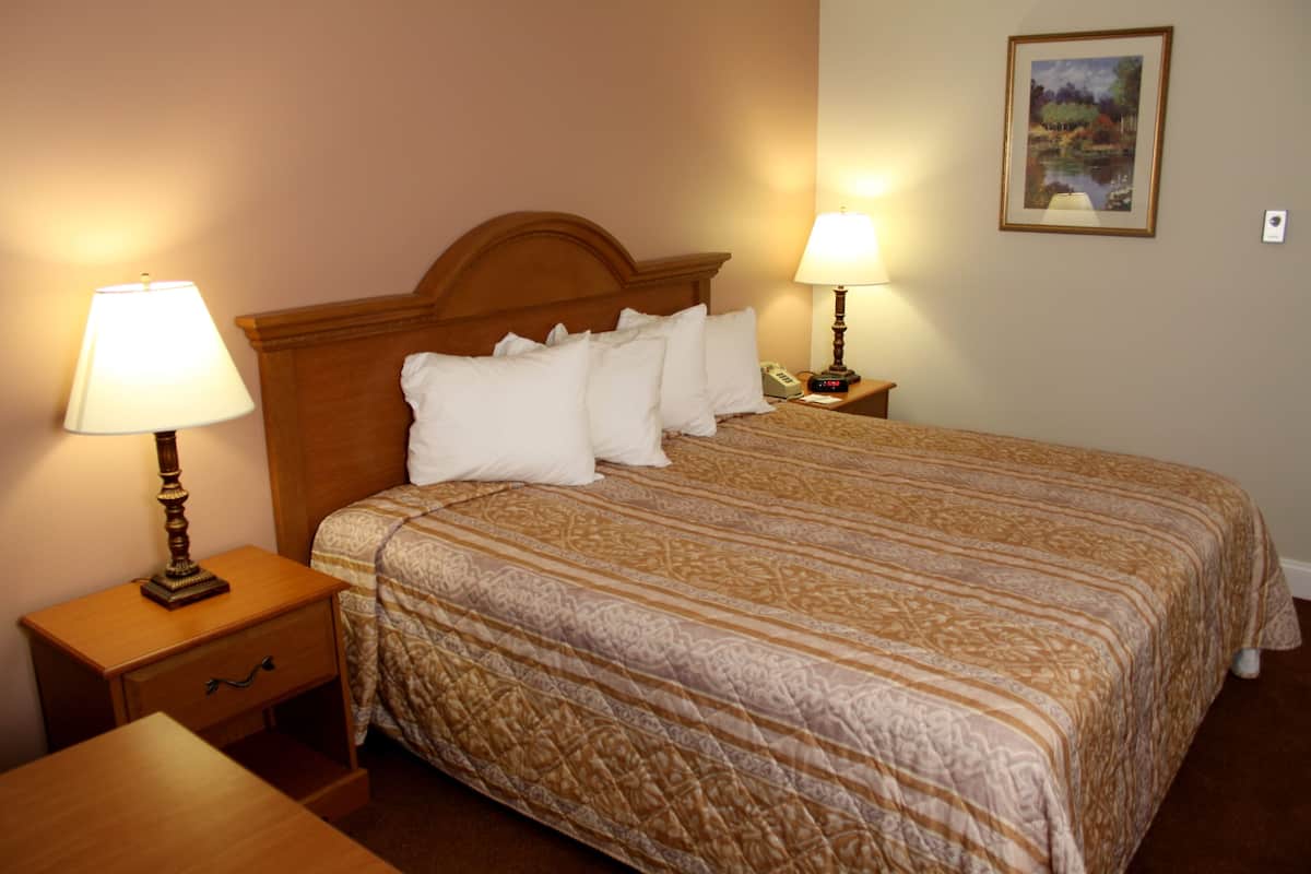 A neatly made bed with a patterned bedspread, two bedside tables with lamps, and a framed picture on the wall.