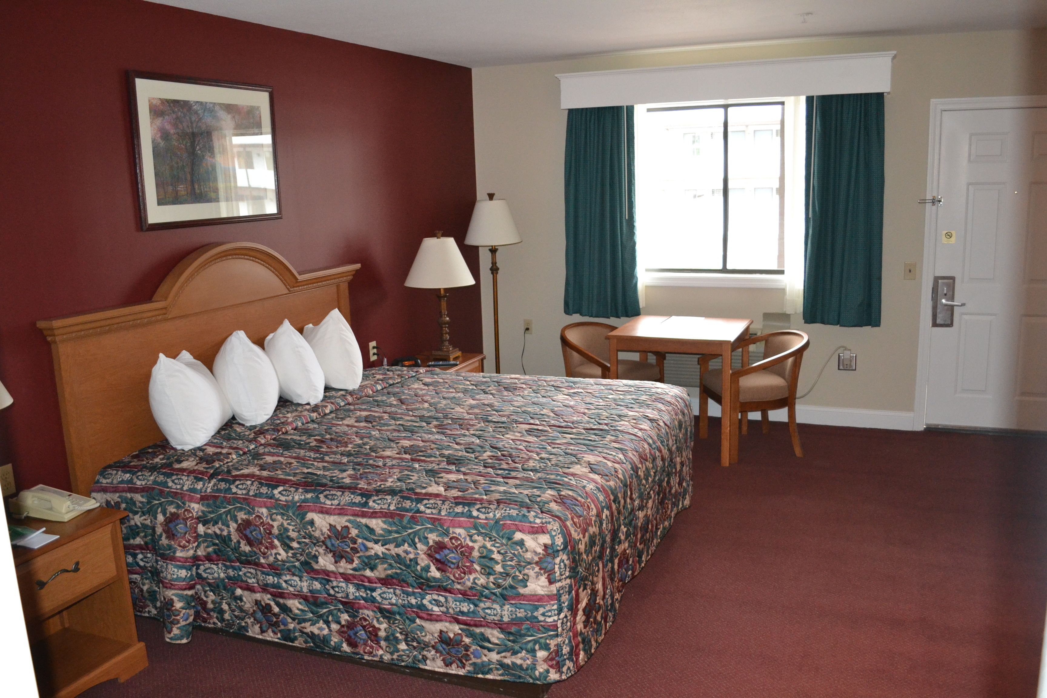 A hotel room with a large bed, a desk, and a chair.