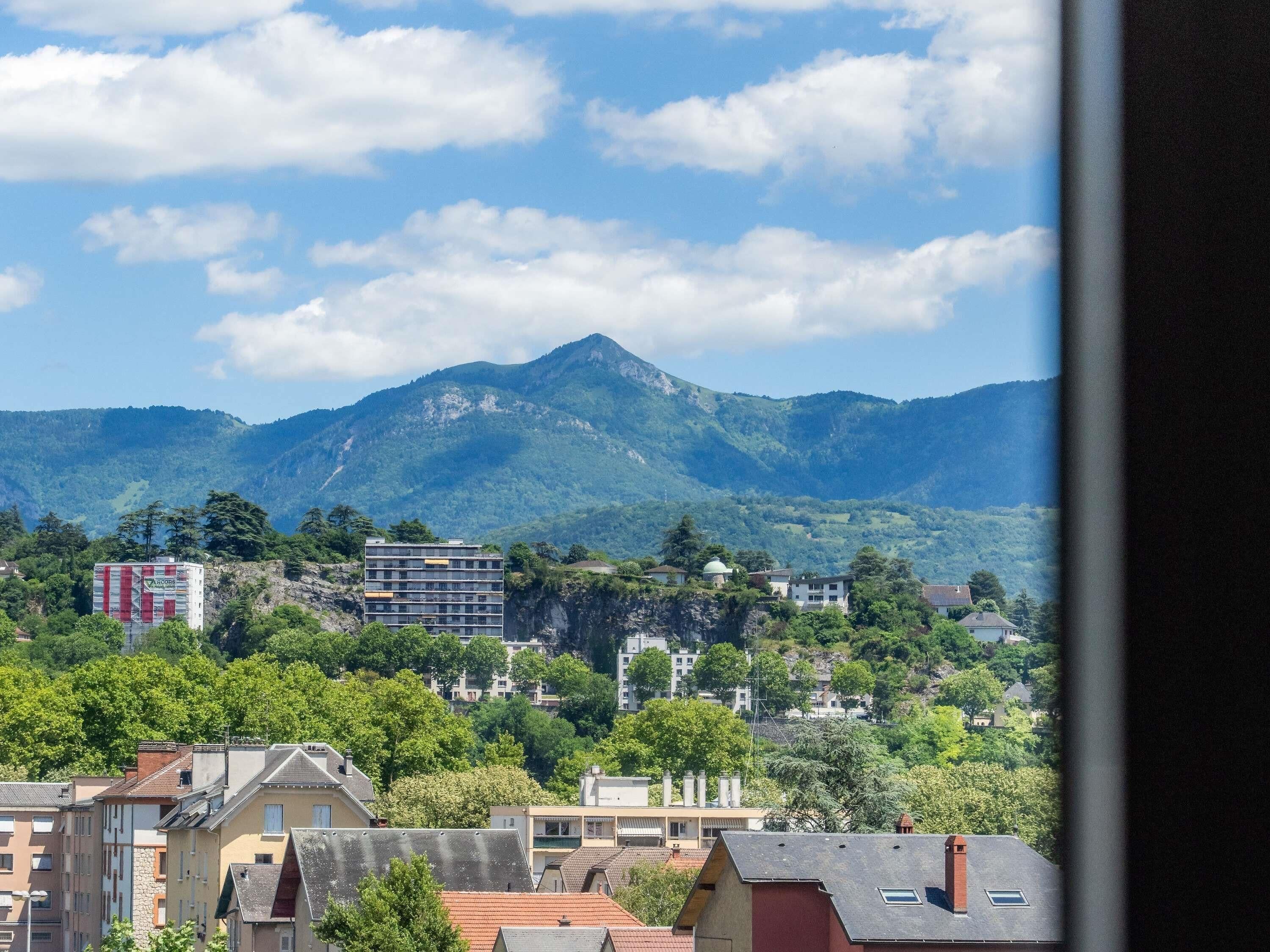 A residential area with buildings, a mountain in the background, and a clear sky.