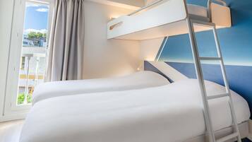 A room with two bunk beds, a window with curtains, a balcony, and a blue accent wall.