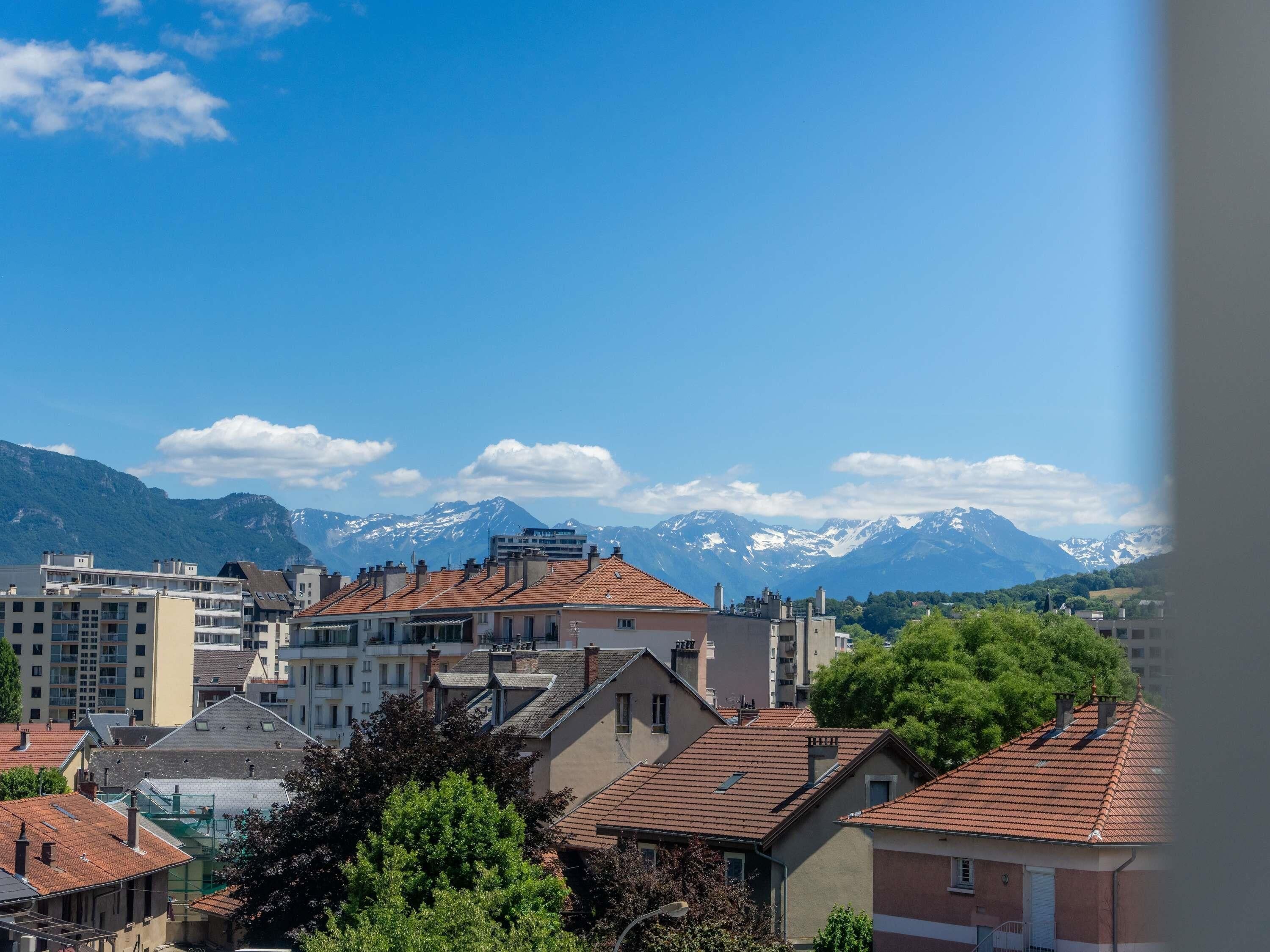 A residential area with buildings, trees, and a mountain range in the background.