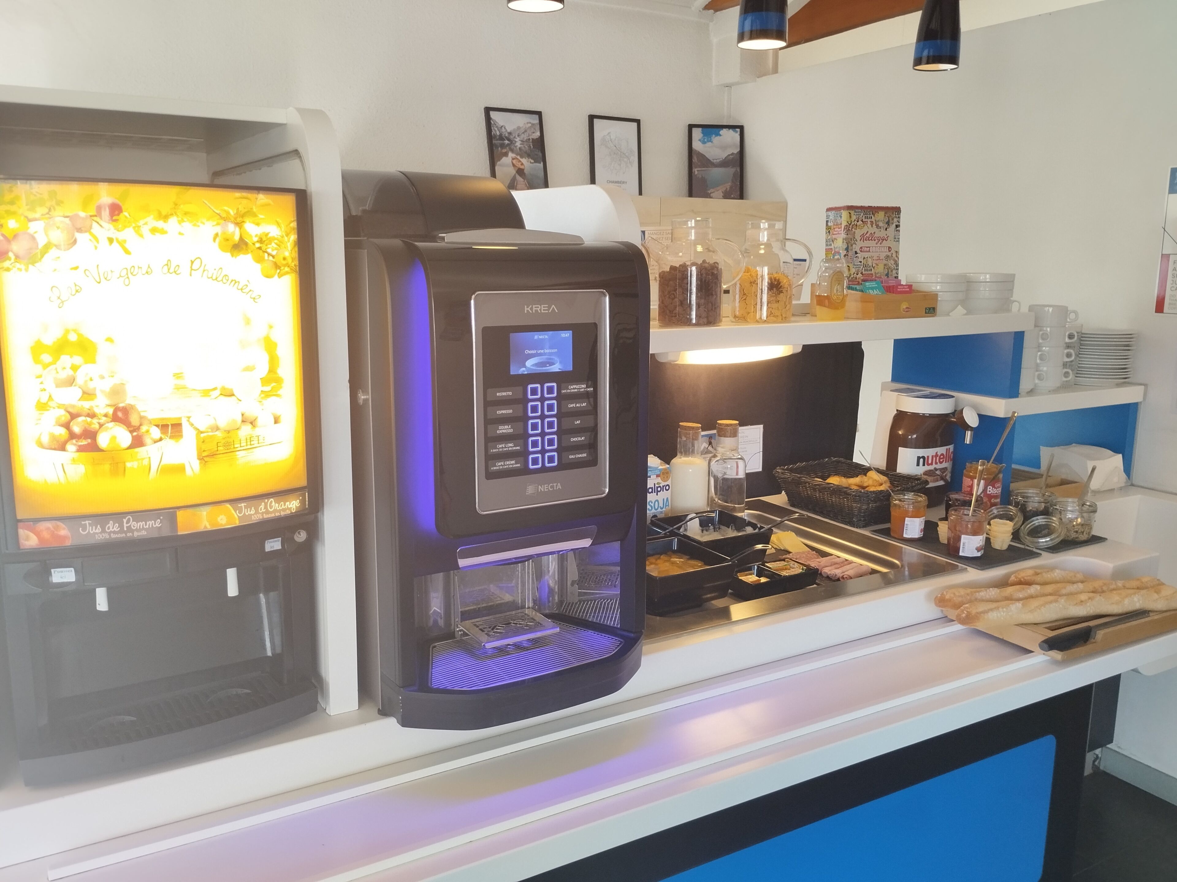 A coffee machine with a digital display and a beverage dispenser, a selection of condiments, and a display of pastries.