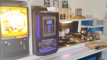 A coffee machine with a digital display and a beverage dispenser, a selection of condiments, and a display of pastries.