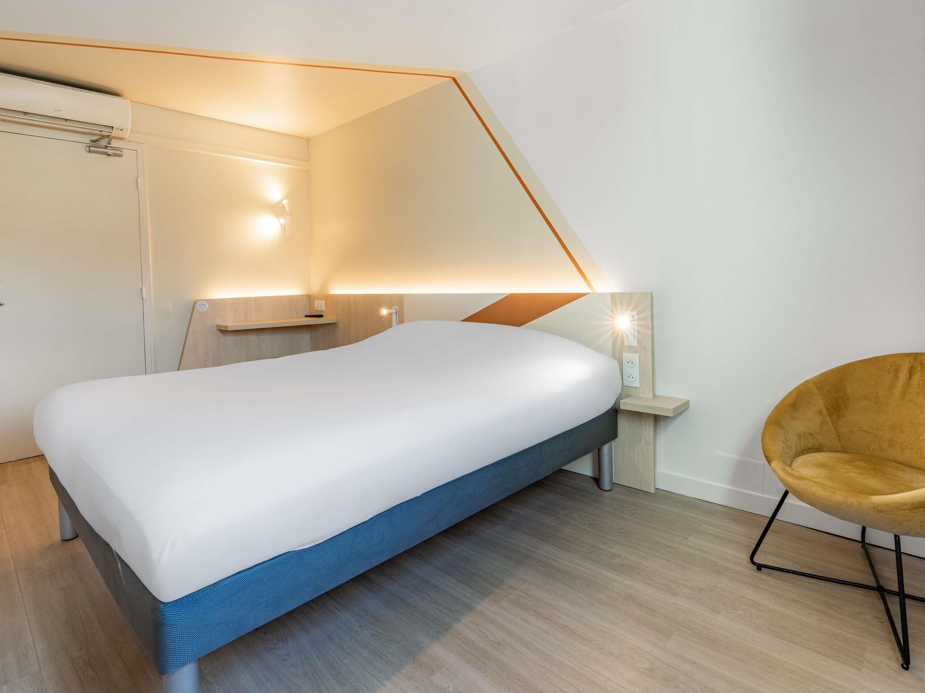 A modern bedroom with a bed, bedside table, and a chair.