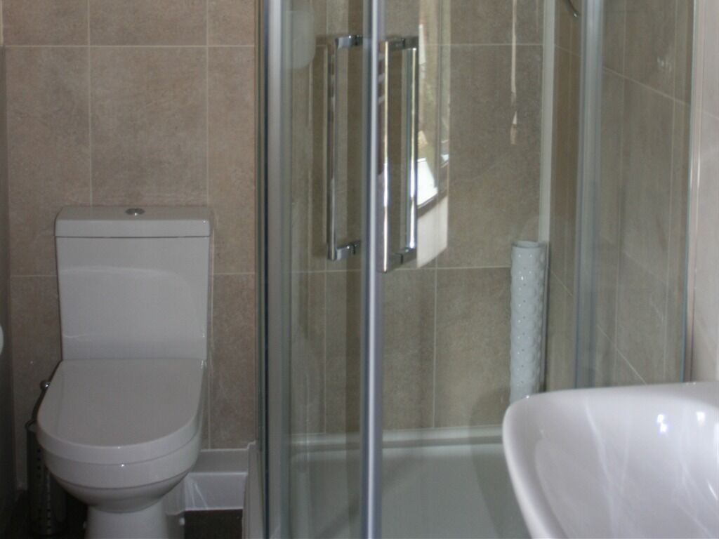 A bathroom with a toilet, a glass shower enclosure, and a white sink.