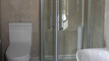 A bathroom with a toilet, a glass shower enclosure, and a white sink.