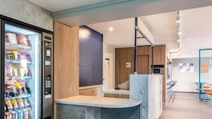 A modern kitchen with a built-in refrigerator, a marble countertop, and a hanging light fixture. - ibis budget Lyon Villefranche sur Saône (Limas)