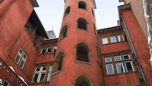 A multi-story building with a central tower, arched windows, and a red facade. - ibis budget Lyon Villefranche sur Saône (Limas)