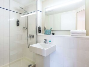 Bathroom features a glass-enclosed shower, sink, and mirror.