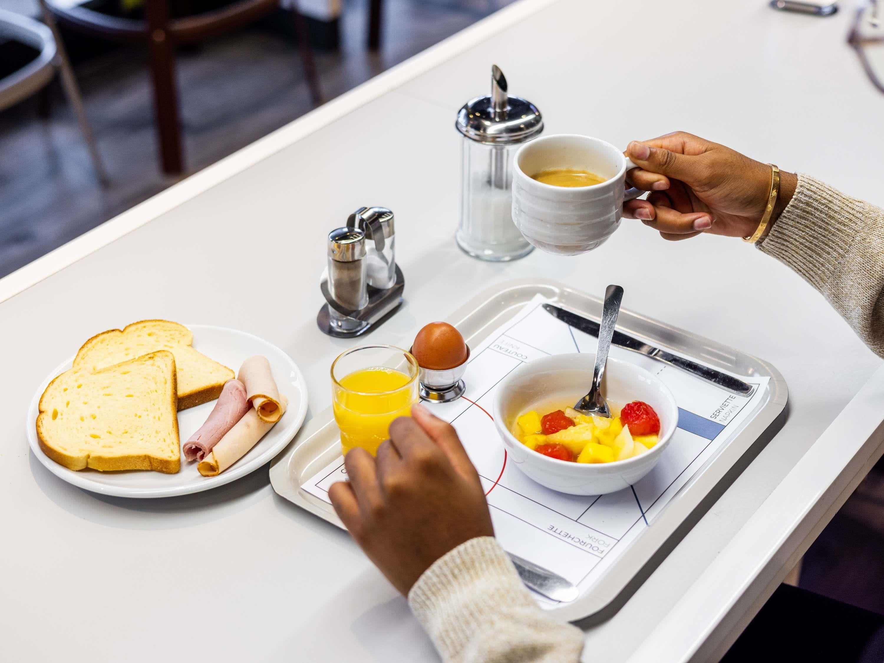 Bandeja de desayuno con tostadas, jamón, huevos y un bol de fruta.