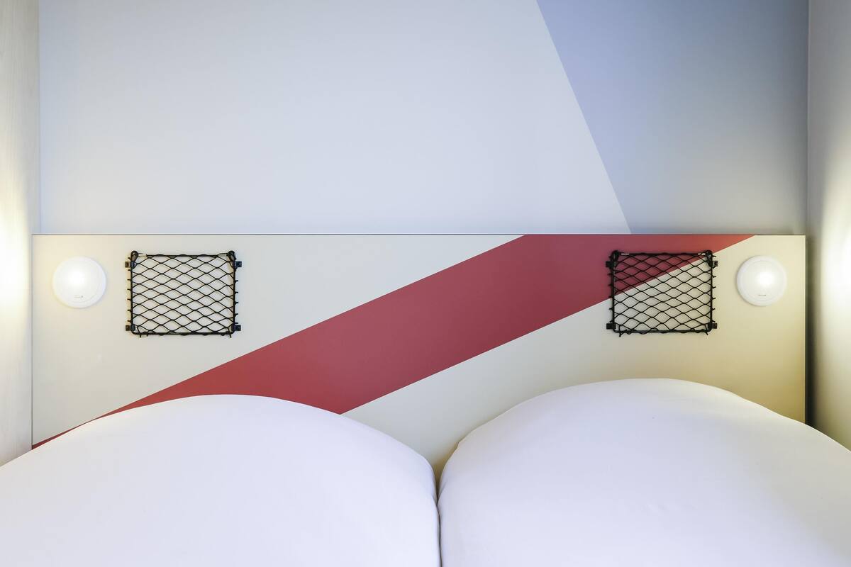 A modern bed with a headboard featuring two mesh panels and a diagonal red accent.