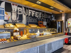 A breakfast buffet with various food items and a coffee machine. - ibis budget Villemomble (Villemomble)