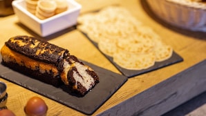 A dessert table with a loaf of bread, a bowl of cookies, and a plate of pastries. - ibis budget Villemomble (Villemomble)