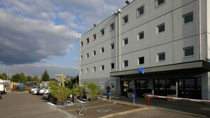 Un hôtel à plusieurs étages doté d’un parking, de places de stationnement réservées aux personnes handicapées et d’une entrée sécurisée par un portail.