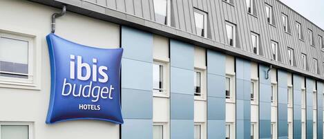 A modern hotel building with a prominent sign for ibis budget hotels.