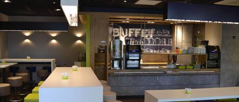 A modern cafe with a long counter, bar stools, and a coffee machine.