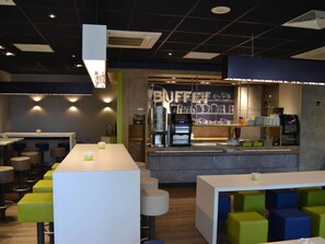 Ein modernes Café mit einer langen Theke, Barhocker und einer Kaffeemaschine.