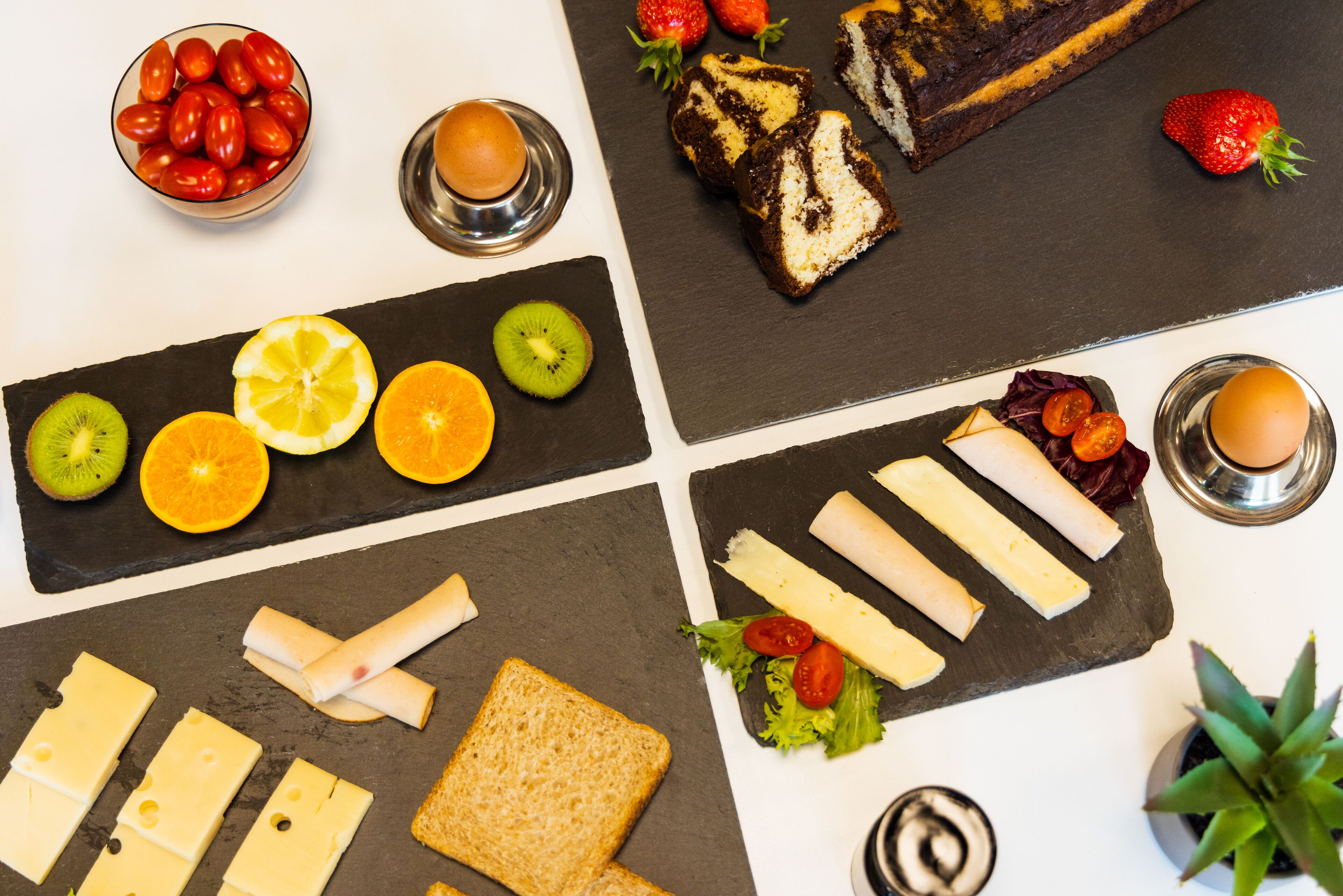 Variedad de alimentos como pan, queso y frutas sobre una tabla de pizarra.