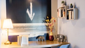 A desk with a laptop, a lamp, a vase with flowers, and a small elephant figurine.