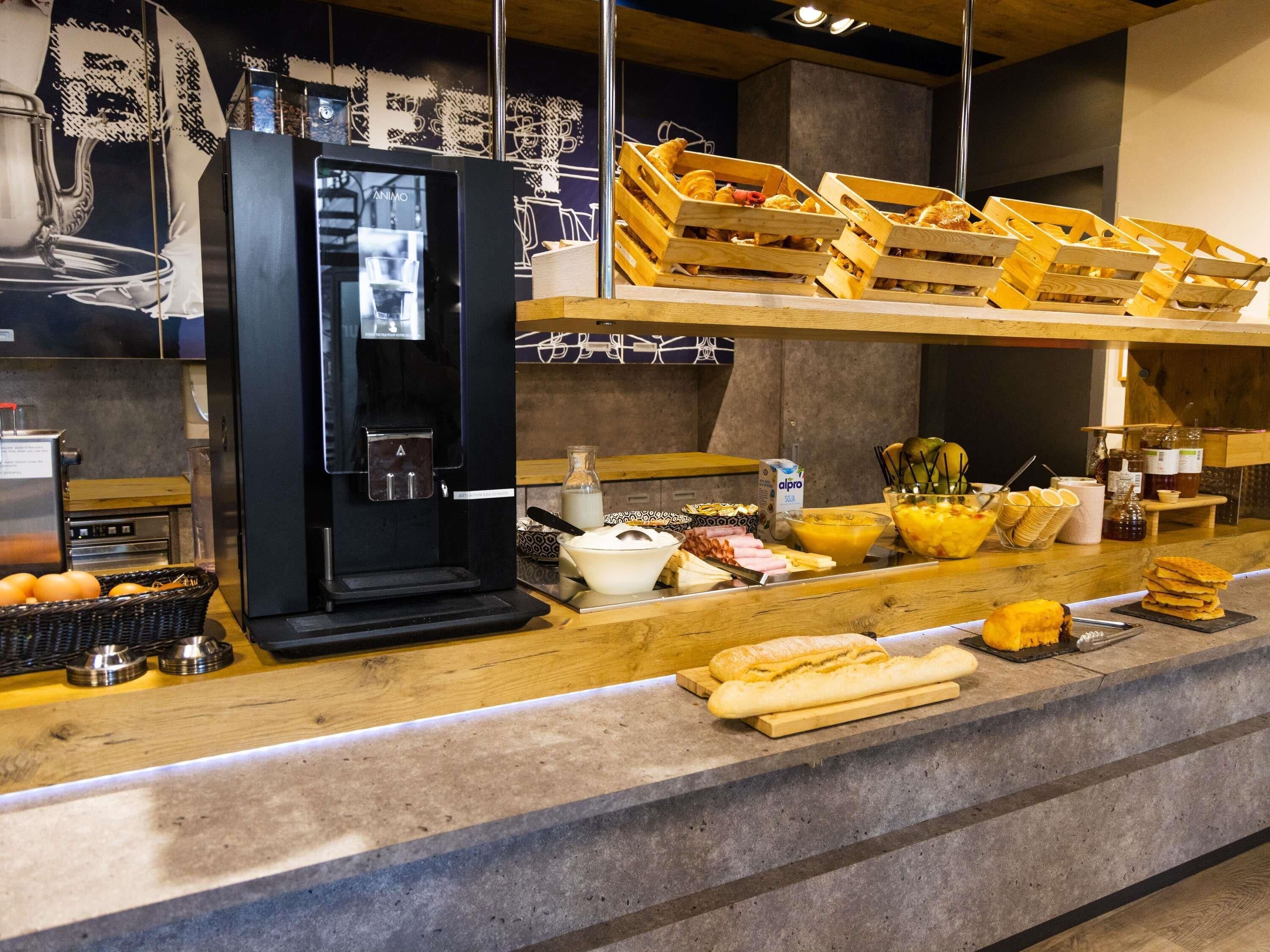 A breakfast bar with a coffee machine, bread, and various breakfast items.